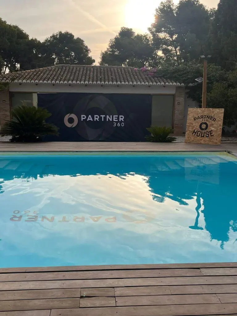 Vista de la piscina y fachada de Partner360 House durante el evento en Valencia con el logotipoen el fondo de la piscina